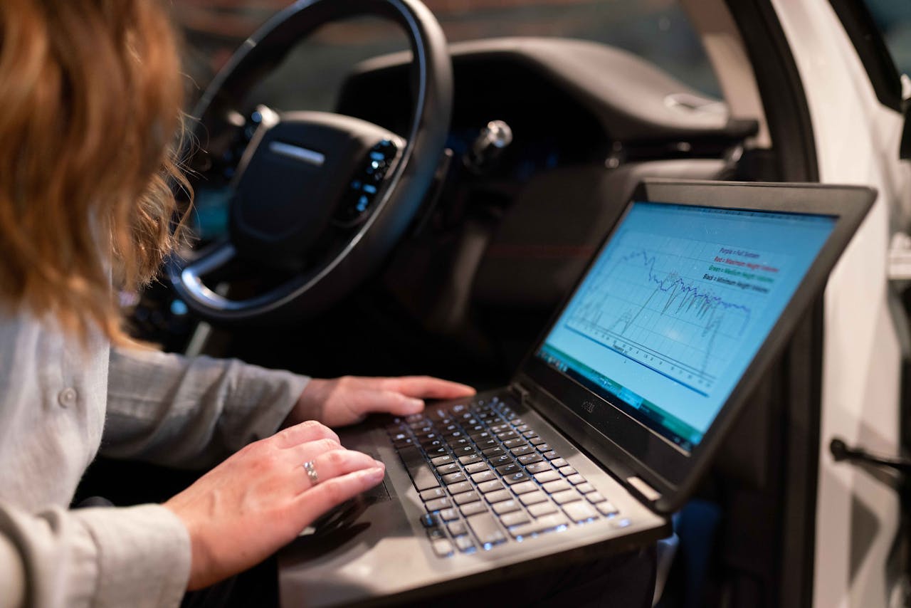 hero-img Female engineer using laptop to analyze vehicle data inside a car for testing purposes.